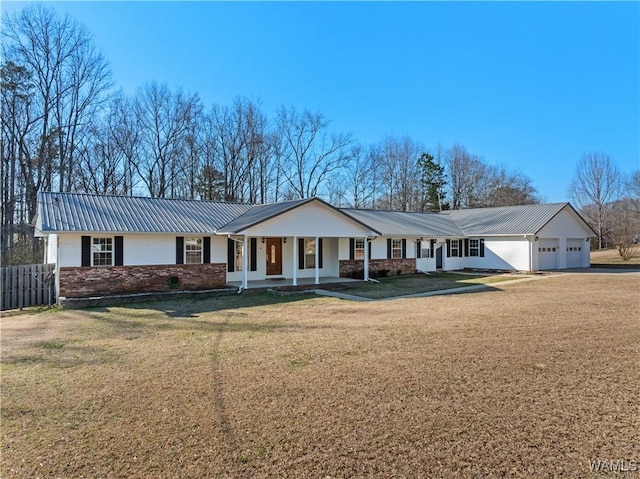 single story home with a garage, metal roof, covered porch, fence, and a front lawn