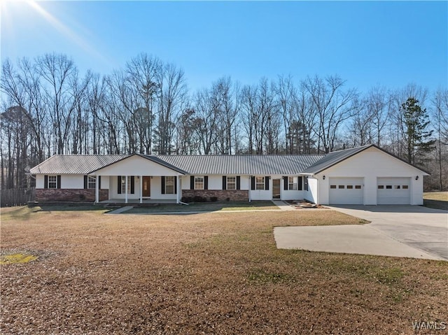 ranch-style house featuring a garage, driveway, metal roof, and a front yard