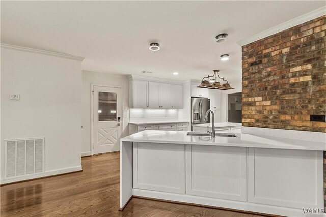 kitchen featuring white cabinetry, sink, stainless steel refrigerator with ice dispenser, hardwood / wood-style flooring, and ornamental molding