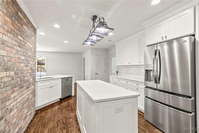 kitchen with brick wall, stainless steel appliances, white cabinetry, and sink