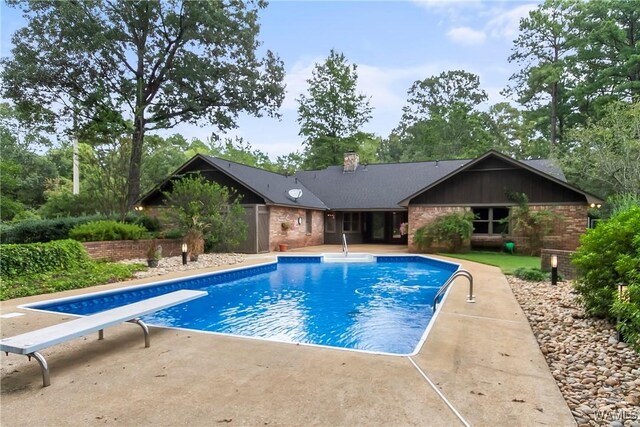 view of swimming pool with a diving board and a patio