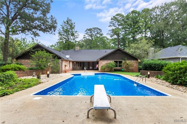 view of swimming pool featuring a diving board