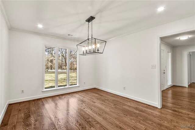 unfurnished dining area featuring a notable chandelier, wood-type flooring, and crown molding