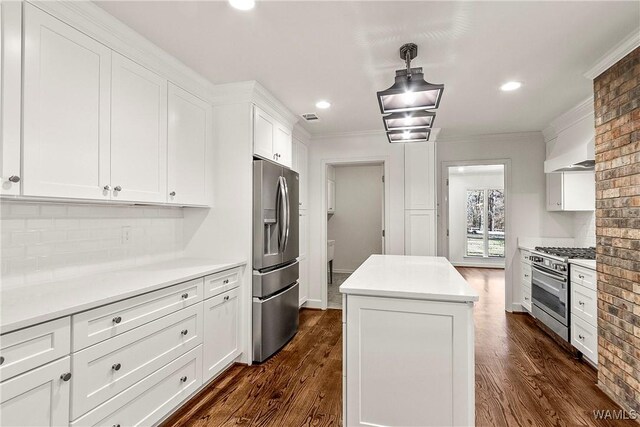 kitchen with a center island, white cabinets, crown molding, appliances with stainless steel finishes, and dark hardwood / wood-style flooring