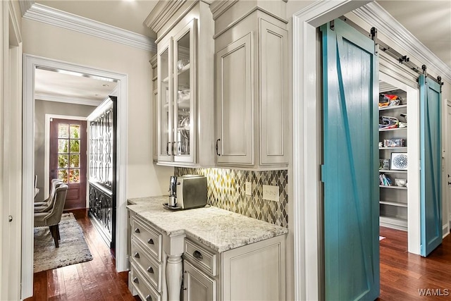 1006 Shady Tree Ln, Tuscaloosa, AL 35406 - interior space featuring light stone counters, a barn door, glass insert cabinets, ornamental molding, and dark wood-style flooring