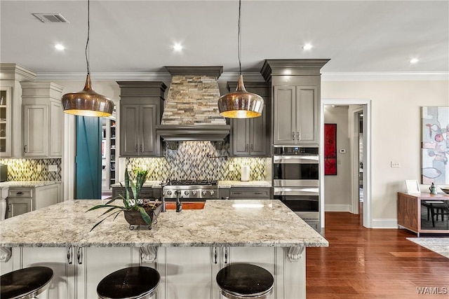 1006 Shady Tree Ln, Tuscaloosa, AL 35406 - kitchen with gray cabinets, light stone counters, double oven, a kitchen breakfast bar, and visible vents