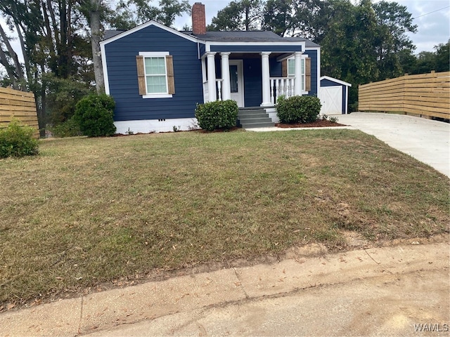 view of front of house with an outbuilding, covered porch, and a front yard