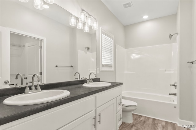 full bathroom with hardwood / wood-style floors, vanity, tub / shower combination, and toilet