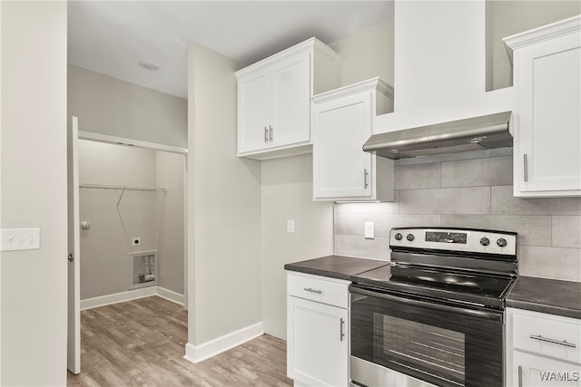 kitchen featuring white cabinets, stainless steel electric range oven, and wall chimney exhaust hood