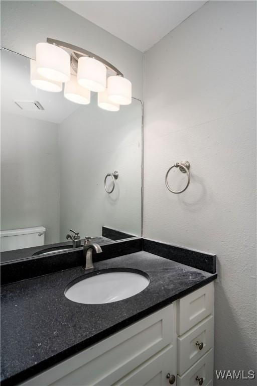 bathroom with vanity, visible vents, and toilet