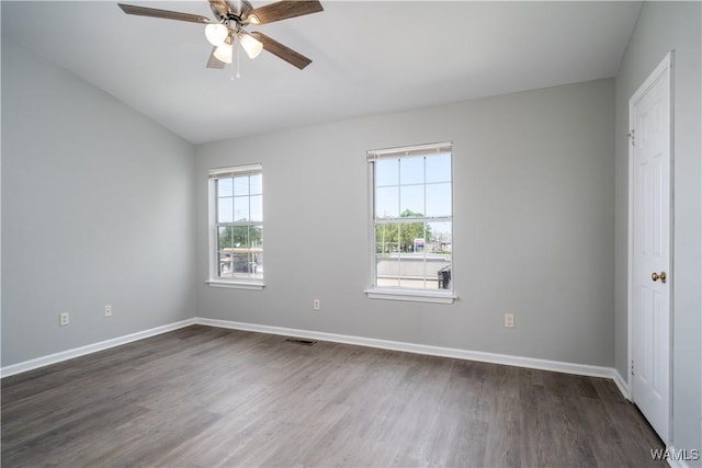 empty room with ceiling fan, dark wood finished floors, visible vents, lofted ceiling, and baseboards