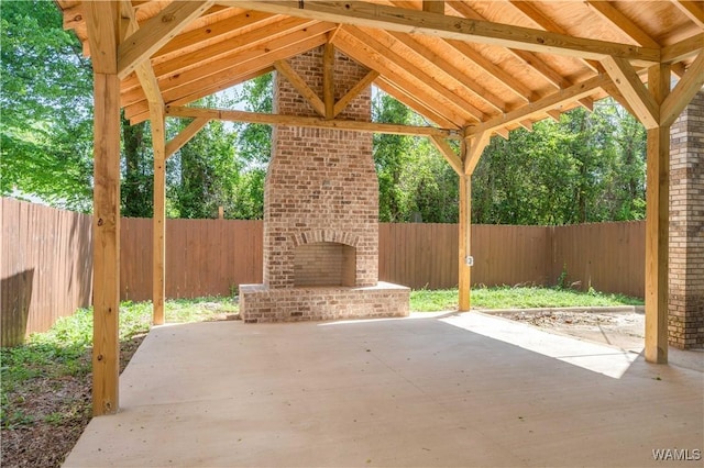 view of patio featuring a fenced backyard, a gazebo, and an outdoor brick fireplace