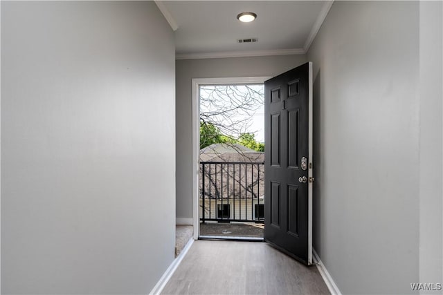entryway with visible vents, baseboards, crown molding, and wood finished floors
