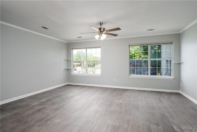 spare room with baseboards, ornamental molding, visible vents, ceiling fan, and wood finished floors