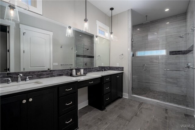 bathroom featuring vanity, a shower with shower door, and tasteful backsplash