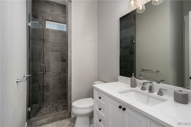 bathroom featuring a shower with door, vanity, and toilet