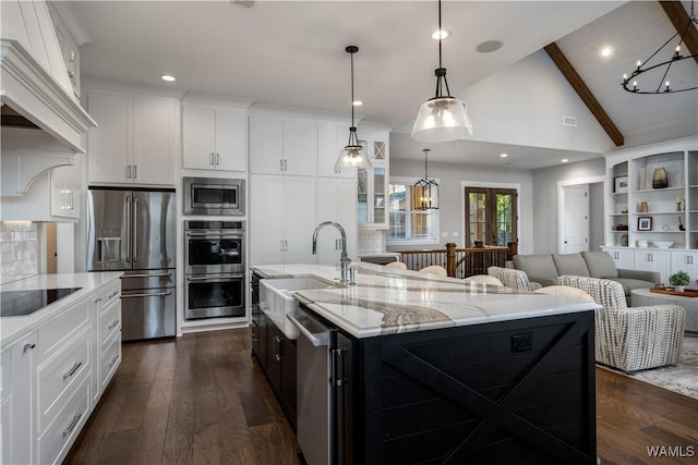 kitchen featuring a large island with sink, white cabinets, appliances with stainless steel finishes, and hanging light fixtures