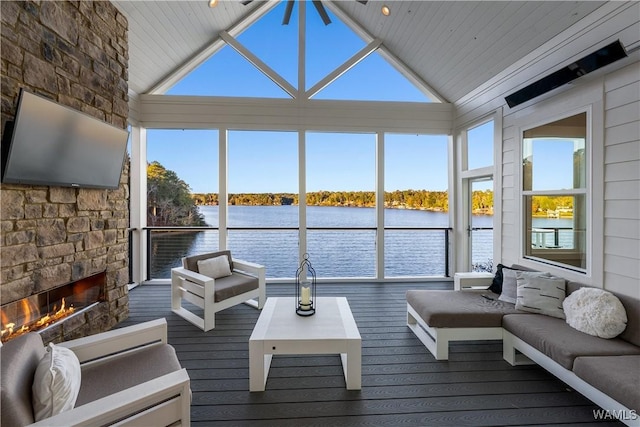 sunroom / solarium with lofted ceiling, a fireplace, a healthy amount of sunlight, and a water view