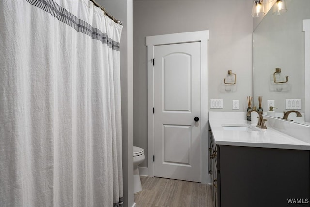 bathroom with toilet, vanity, and hardwood / wood-style flooring