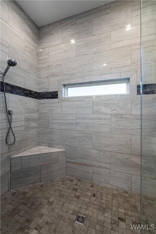 bathroom with a tile shower and a wealth of natural light