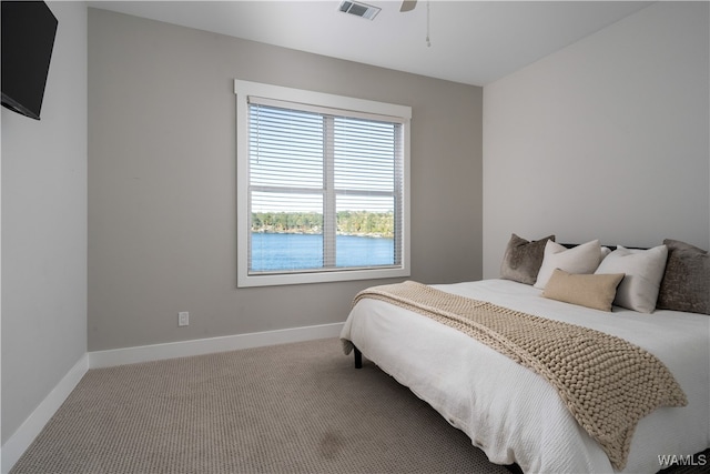 bedroom with ceiling fan, carpet flooring, and a water view