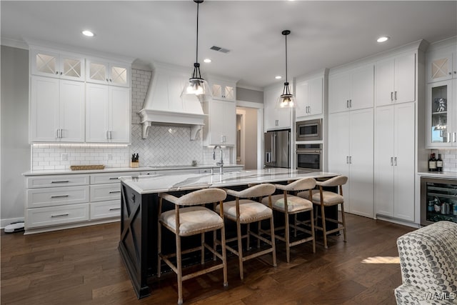 kitchen with stainless steel appliances, white cabinetry, and an island with sink