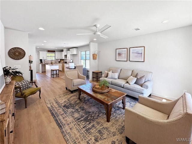 living room with light hardwood / wood-style flooring and ceiling fan