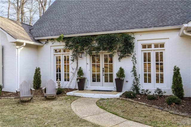 property entrance with a shingled roof, french doors, and brick siding