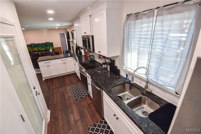 3207 33rd St, Northport, AL 35476 - kitchen featuring dark stone counters, a sink, dark wood-type flooring, white cabinets, and appliances with stainless steel finishes