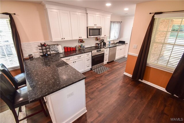 3207 33rd St, Northport, AL 35476 - kitchen with tasteful backsplash, stainless steel appliances, white cabinets, and dark wood-style floors