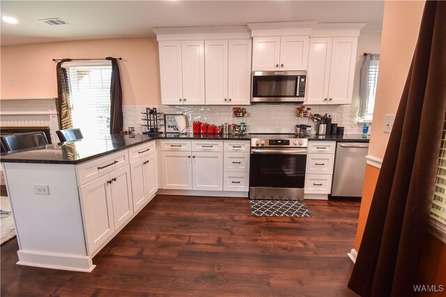 3207 33rd St, Northport, AL 35476 - kitchen with appliances with stainless steel finishes, dark wood-style flooring, white cabinetry, visible vents, and a peninsula