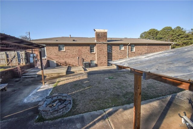 3207 33rd St, Northport, AL 35476 - back of house with a fire pit, a chimney, central AC, and brick siding