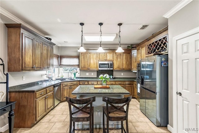 2940 Lake Crest Dr, Tuscaloosa, AL 35406 - kitchen with appliances with stainless steel finishes, light tile patterned floors, a kitchen island, crown molding, and brown cabinets