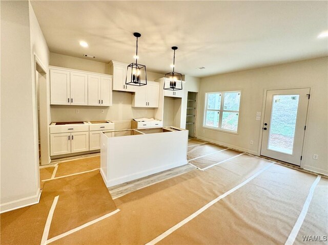 kitchen featuring sink, white cabinetry, hanging light fixtures, a center island with sink, and dark stone counters