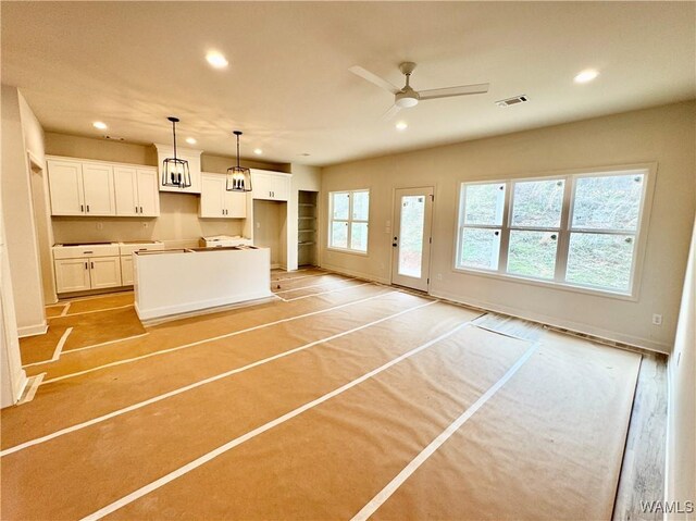 kitchen featuring sink, white cabinetry, tasteful backsplash, dark stone countertops, and an island with sink