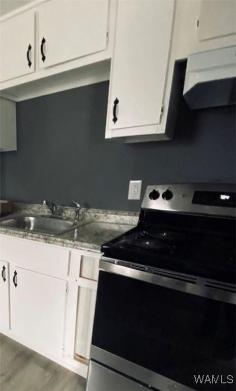 kitchen featuring white cabinetry, stainless steel electric range oven, sink, and range hood