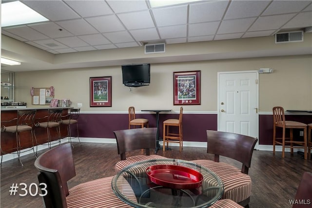 living room featuring a paneled ceiling and dark wood-type flooring