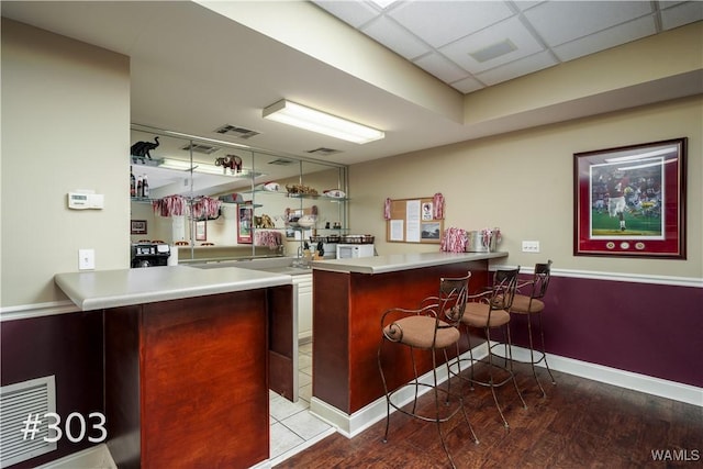 bar featuring hardwood / wood-style floors and a drop ceiling