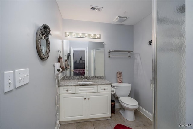 bathroom with tile patterned flooring, vanity, toilet, and walk in shower