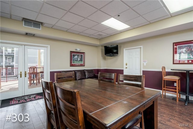 dining room with dark hardwood / wood-style flooring, a wealth of natural light, a drop ceiling, and french doors