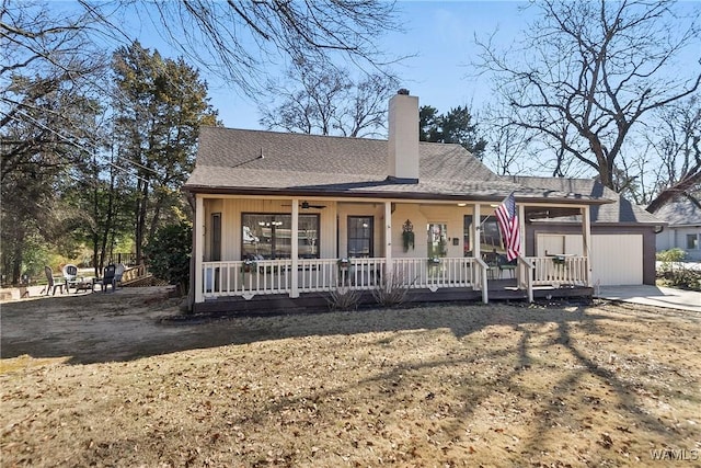 view of front facade with an outbuilding, covered porch, roof with shingles, and a chimney