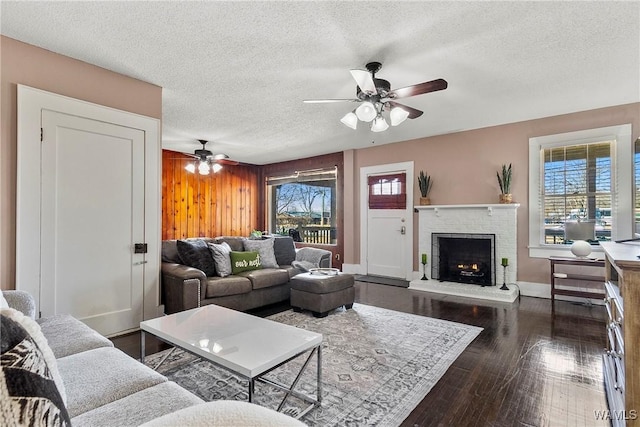 living room with a textured ceiling, wood walls, plenty of natural light, and dark wood finished floors