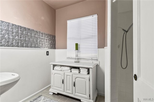 full bath featuring a sink, tile patterned flooring, and a tile shower