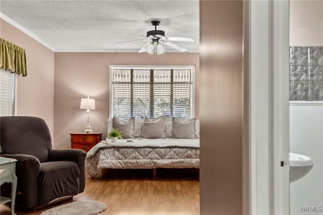 bedroom with hardwood / wood-style flooring, ceiling fan, crown molding, and a textured ceiling