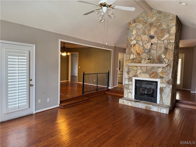 unfurnished living room featuring a ceiling fan, lofted ceiling with beams, wood finished floors, a textured ceiling, and a fireplace