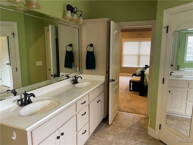 ensuite bathroom featuring tile patterned flooring, a sink, and double vanity