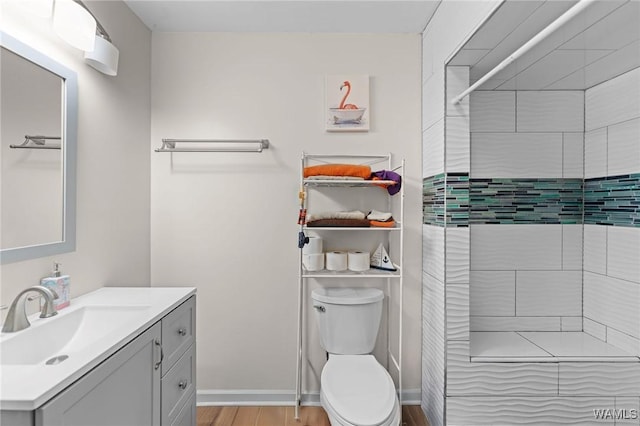 12515 Bone Camp Rd, Northport, AL 35475 - bathroom featuring vanity, toilet, tiled shower, wood finished floors, and baseboards