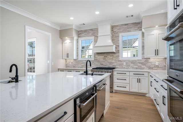 kitchen with white cabinets, stainless steel oven, sink, and premium range hood