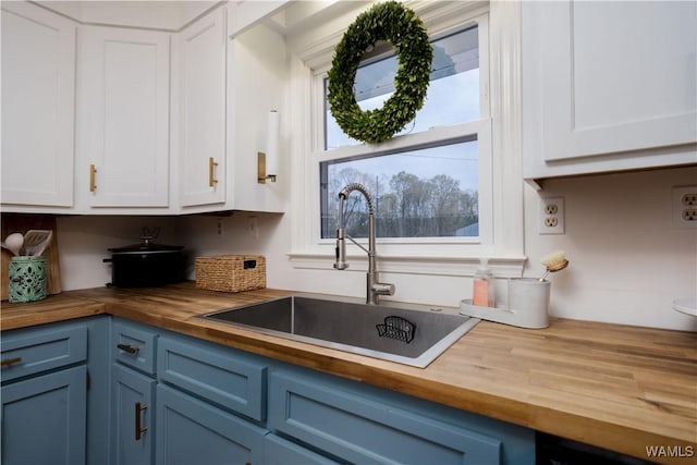 kitchen with wooden counters, a sink, and blue cabinetry