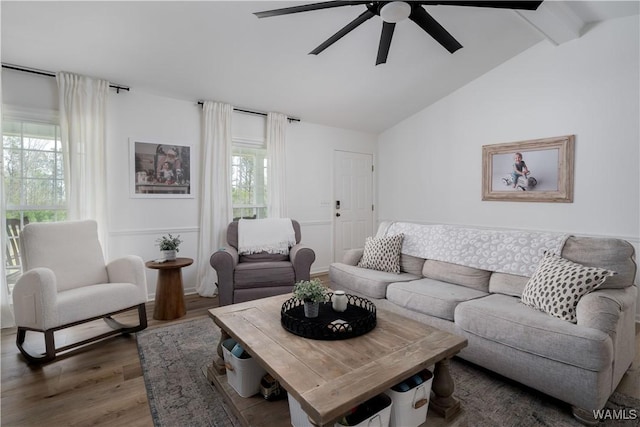 living room with wood finished floors, ceiling fan, and vaulted ceiling with beams